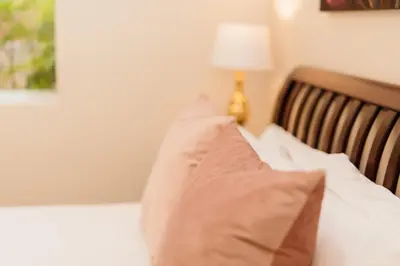 a bed with a pillow and a lamp in a room at Protea Garden Cottage in Stellenbosch