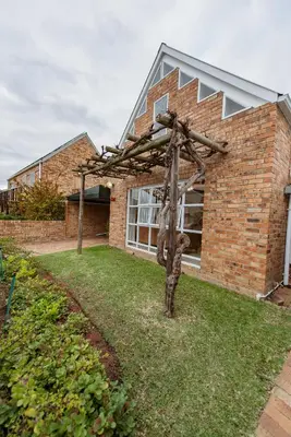 a house with a wooden structure in the yard at Protea Garden Cottage in Stellenbosch