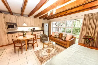 a kitchen and living room with a couch and a table at Protea Garden Cottage in Stellenbosch