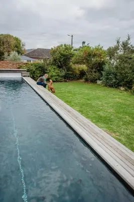 a man and a child sitting next to a swimming pool at Protea Garden Cottage in Stellenbosch