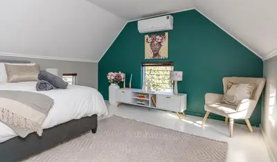 a bedroom with a green wall and a bed and a chair at Home in Durbanville in Oakdale