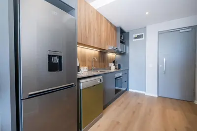 a kitchen with a stainless steel refrigerator and wooden cabinets at 413 Riverlands - 1 Bedroom Apartment with Parking in Cape Town