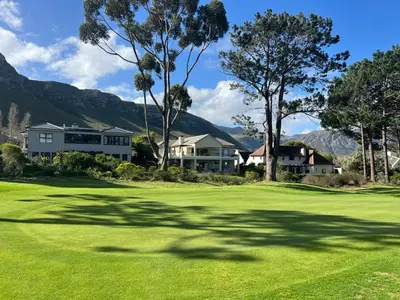a view of a golf course with mountains in the background at Golfers delight in Hermanus
