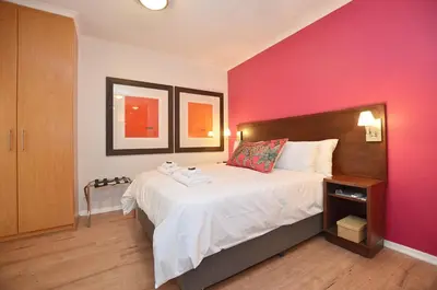 a bedroom with a large bed with a pink wall at The Sleep Easy in the Old Town Stellenbosch in Stellenbosch