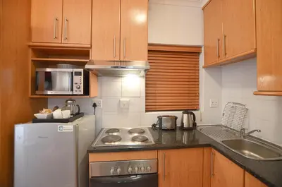 a kitchen with wooden cabinets and a white refrigerator at The Sleep Easy in the Old Town Stellenbosch in Stellenbosch