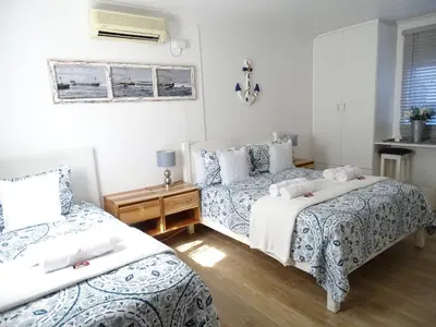 a bedroom with two beds and a table and a window at Big Skies Guesthouse in Gordonʼs Bay