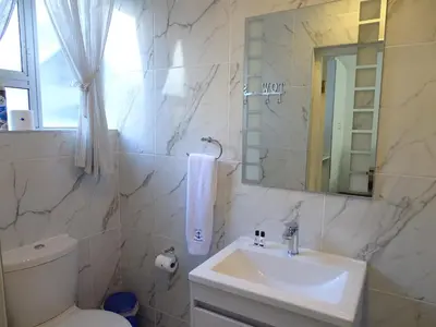 a bathroom with a sink and a toilet and a mirror at Big Skies Guesthouse in Gordonʼs Bay