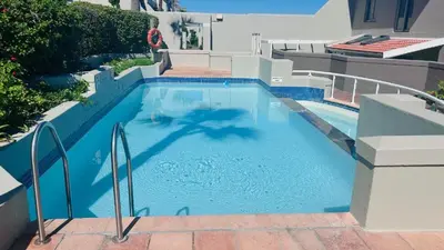 a swimming pool with blue water in a building at Salt & Sandy Shores Dolphin Beach Blouberg in Cape Town