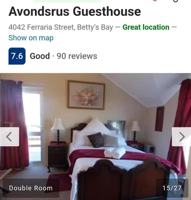 a bedroom with a large bed with red curtains at Avondsrus Guesthouse in Bettyʼs Bay