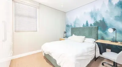a bedroom with a bed and a desk and a chair at Andringa Walk, Modern 2 Bedroom Apartment in Stellenbosch
