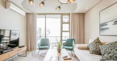 a living room with a couch and chairs and a television at Andringa Walk, Modern 2 Bedroom Apartment in Stellenbosch