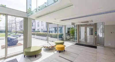 a lobby with two chairs and a table and windows at Andringa Walk, Modern 2 Bedroom Apartment in Stellenbosch