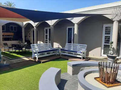 a patio with white benches and a blue canopy at Simply The Choice Manor in Cape Town