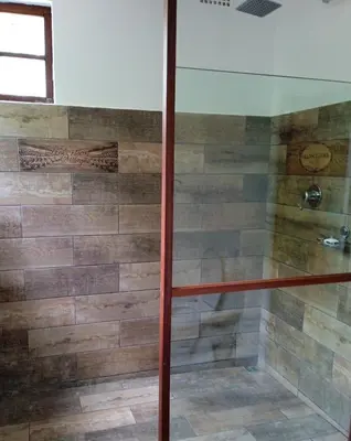 a shower in a bathroom with wooden tiles at Groendraai PetFriendly SelfCatering Accommodation, Die Karoohuis, Die Wijnhuis and Die Vinknes