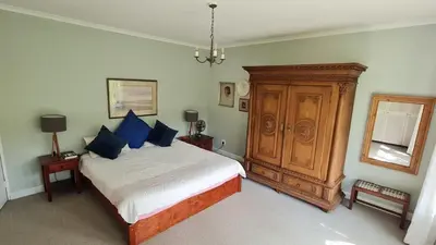 a bedroom with a bed and a wooden cabinet at Tranquil Stylish Home with Nature Pool near Reserve in Somerset West