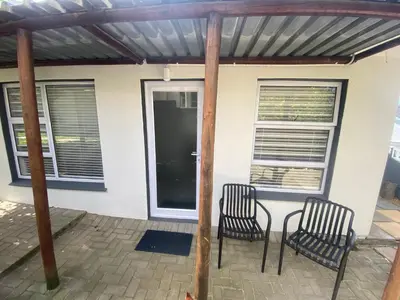 a patio with two chairs and a table in front of a house at Garden flat Durbanville - with Office, WiFi and secure gated parking in Eversdal