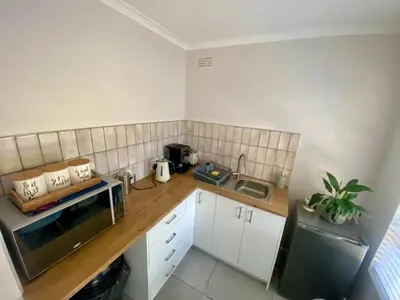 a kitchen with a counter with a microwave and a sink at Garden flat Durbanville - with Office, WiFi and secure gated parking in Eversdal