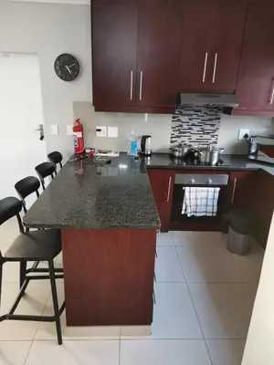 a kitchen with brown cabinets and a counter top at Cosy 3 bedroom in Cape Town