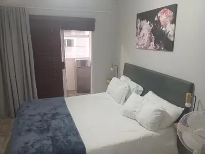 a bedroom with a bed with white sheets and pillows at Cosy 3 bedroom in Cape Town