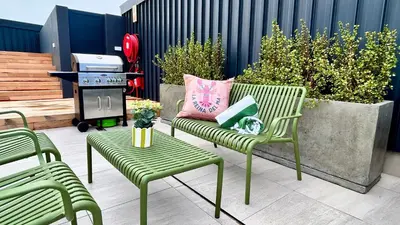 a patio with two green chairs and a grill at Whale Walk Apartment in Hermanus