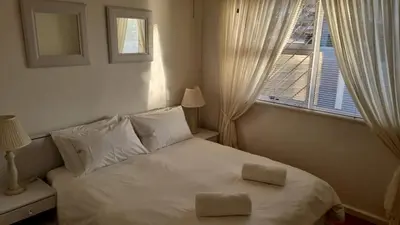 a bedroom with a white bed with two pillows on it at 3 On Herschell in Strand