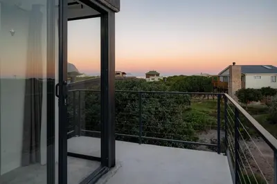 a balcony with a view of the sunset at The Glass House Loft in Bettyʼs Bay