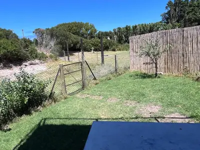 a fence with a gate in a yard at The Glass House Loft in Bettyʼs Bay