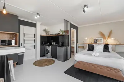 a bedroom with a large bed and a kitchen at San Norina Gardens 5 in Cape Town