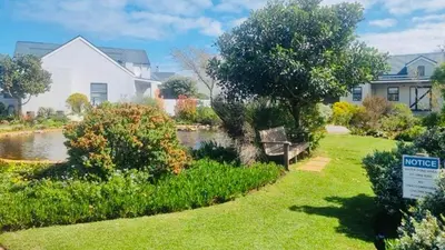 a park with a bench in front of a house at Columbus Haven in Hermanus