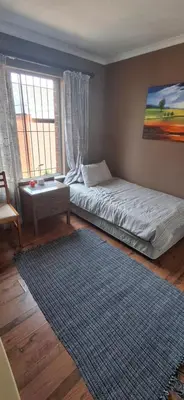 a bedroom with a bed and a rug and a window at Pug's Room in Welgemoed