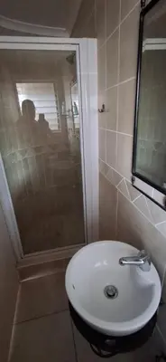 a bathroom with a white sink and a shower at Pug's Room in Welgemoed