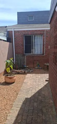 a brick building with a window and a potted plant at Pug's Room in Welgemoed