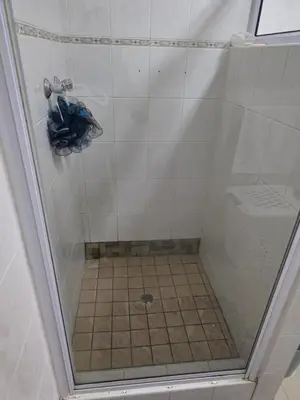 a shower with a glass door and a tile floor at Peters Place