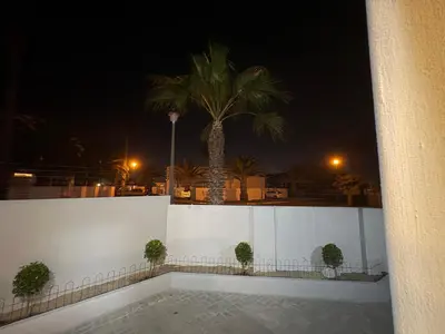 a white fence with a palm tree in the background at Serenity suite 6 minutes away from the beach in Cape Town