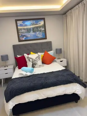 a bedroom with a large bed with colorful pillows at Serenity suite 6 minutes away from the beach in Cape Town