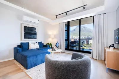 a living room with a blue couch and a large window at 511 Riverlands - Lux 2 Bedroom Apartment with Parking in Cape Town