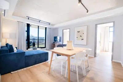 a living room with a table and a blue couch at 511 Riverlands - Lux 2 Bedroom Apartment with Parking in Cape Town