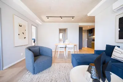 a living room with blue chairs and a table at 511 Riverlands - Lux 2 Bedroom Apartment with Parking in Cape Town