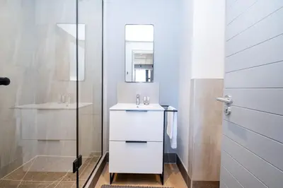 a white bathroom with a sink and a mirror at 511 Riverlands - Lux 2 Bedroom Apartment with Parking in Cape Town