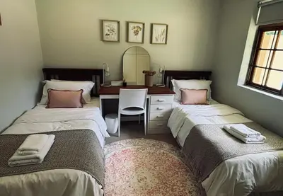 two beds in a room with a desk and a mirror at Family home with table mountain view and pool in Stellenbosch
