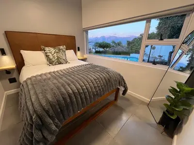 a bedroom with a bed and a large window at Durr's Nest - Central Paarl Mountain Retreat in Paarl