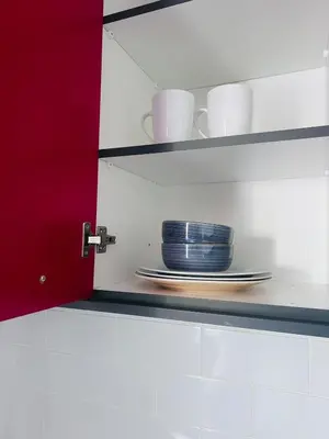 a shelf with plates and cups in a kitchen at Entire Modern, Secure & Central Flat in Milnerton in Cape Town
