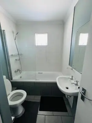 a white bathroom with a toilet and a sink at Entire Modern, Secure & Central Flat in Milnerton in Cape Town