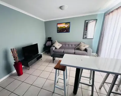 a living room with a couch and a table at Entire Modern, Secure & Central Flat in Milnerton in Cape Town