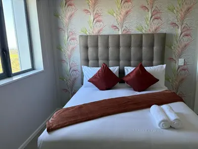 a bedroom with a large bed with red pillows at 2 Bed Executive Apartment Table Mountain views in Cape Town