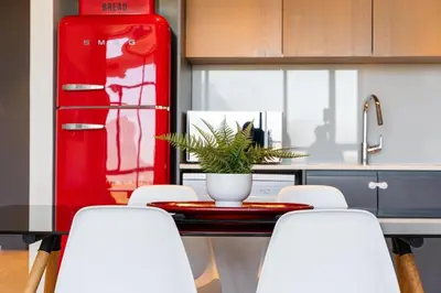a kitchen with a table with chairs and a red refrigerator at 2 Bed Executive Apartment Table Mountain views in Cape Town