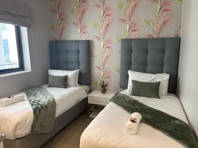 a bedroom with two beds and a wallpaper with flowers at 2 Bed Executive Apartment Table Mountain views in Cape Town