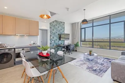 a kitchen and living room with a glass table and chairs at 2 Bed Executive Apartment Table Mountain views in Cape Town
