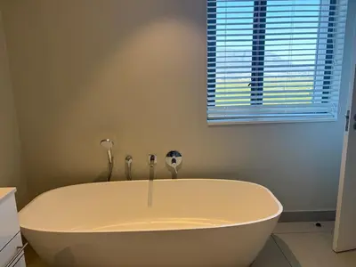 a white bath tub in a bathroom with a window at 2 Bed Executive Apartment Table Mountain views in Cape Town