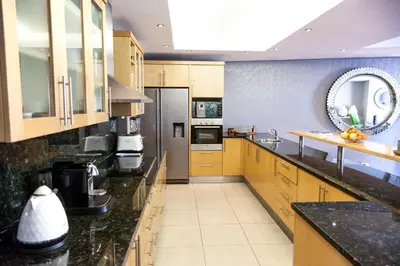 a large kitchen with wooden cabinets and black counter tops at Cape Town Sunset Beach Luxury Beachfront Villa in Cape Town